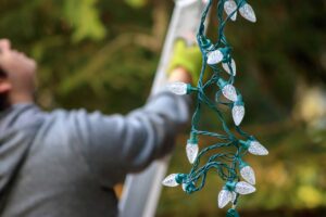 Man,In,Gray,Holding,Christmas,Lights,Climbs,Ladder